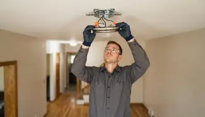 Electrician installing and wiring a ceiling light fixture in an Ogden, UT home