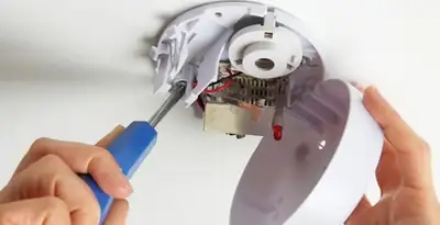 Certified technician wiring smoke detector during installation in Ogden, UT